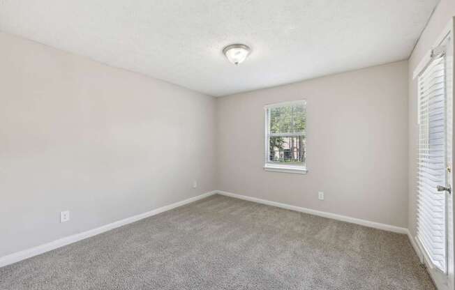 A carpeted bedroom with a window at Gwinnett Square Apartments in Duluth, GA