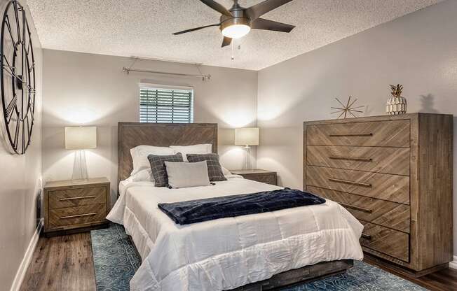 A bedroom with a bed, dresser, and ceiling fan.
