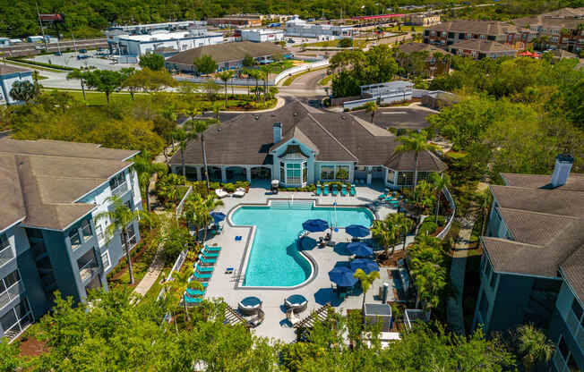 an aerial view of the resort style pool with lounge chairs and umbrellas