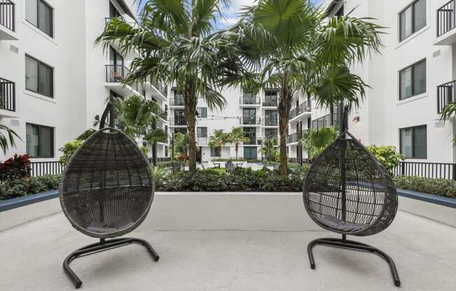 two chairs in front of an apartment building with palm trees