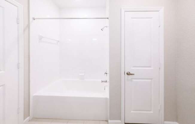 a white bathroom with a tub and a closet