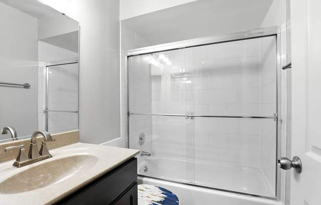 A bathroom with a sink, mirror, and shower.