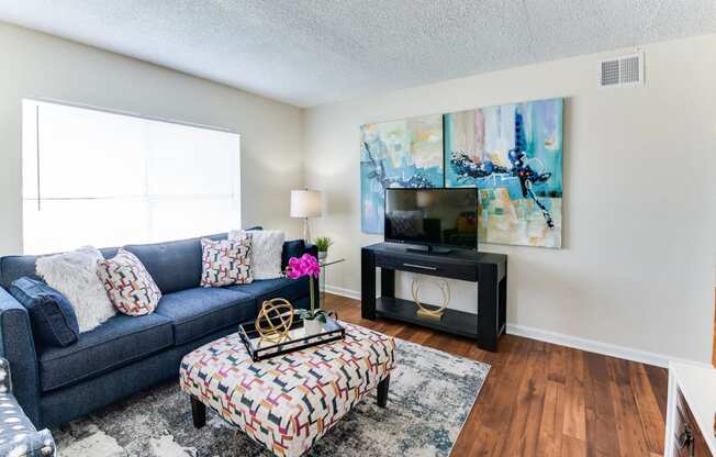 a living room with a blue couch and a tv on a stand in front of a window