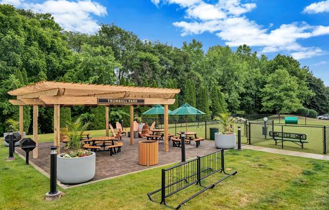 a pavilion with a seating area and a dog park in the background