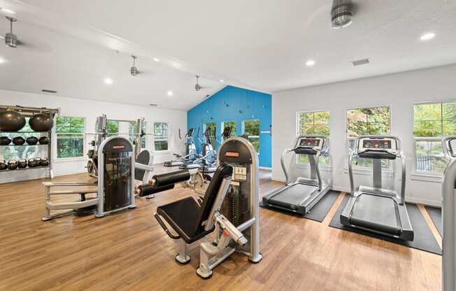 the gym with treadmills and other exercise equipment on a wooden floor