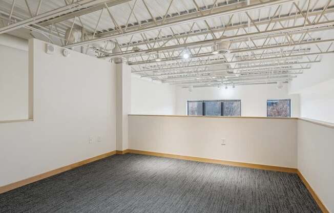 A room with a grey carpet and a white ceiling with a window.