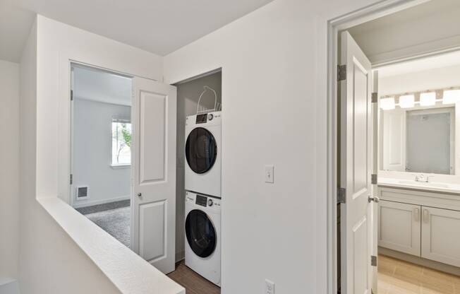 a washer and dryer in a living room with a door to a kitchen