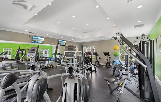 A gym with a variety of equipment including treadmills, stationary bikes, and weight machines.