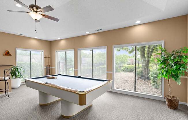 A pool table in a room with a ceiling fan and sliding glass doors.