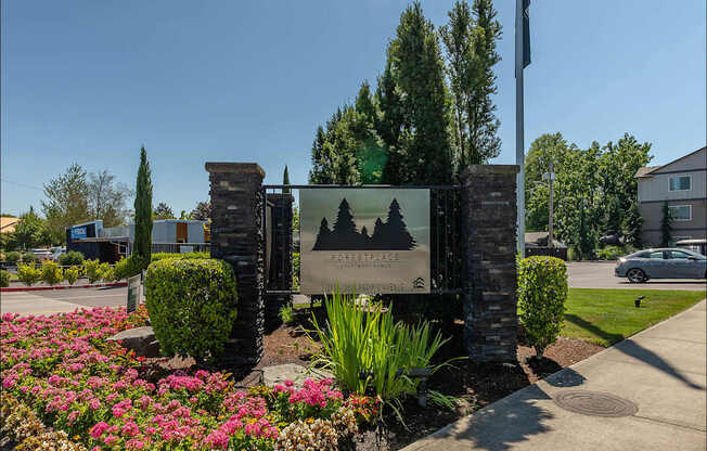 A sign for Forest Springs Estates is surrounded by flowers and greenery at Forestplace Apartment Homes, Forest Grove, OR