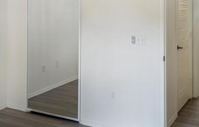 A room with a white door and a mirror on the wall.