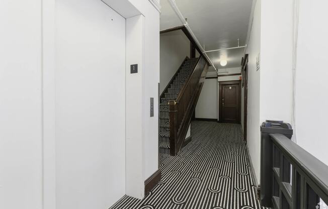 a hallway with stairs and a black and white geometric flooring at Clay & Tiffany, Portland, OR, 97201