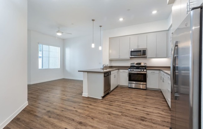 an empty kitchen with white cabinets and stainless steel appliances at Metro Gateway, Riverside, CA