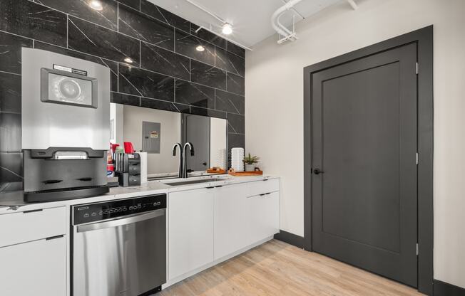 a kitchen with white cabinets and stainless steel appliances and a black door