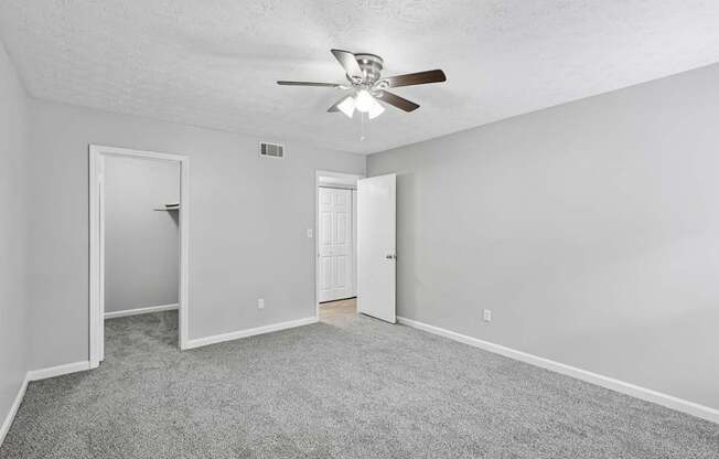A room with a ceiling fan and carpeted floor.
