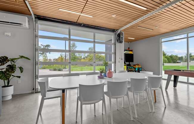 a dining room with white tables and chairs and large windows