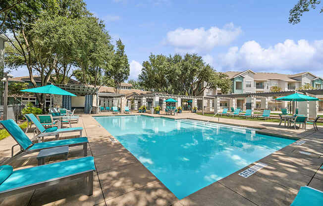 Community Swimming Pool with Pool Furniture at Essence Apartments in Dallas, TX.