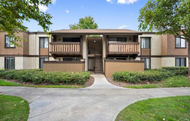 an apartment building with two balconies and a sidewalk