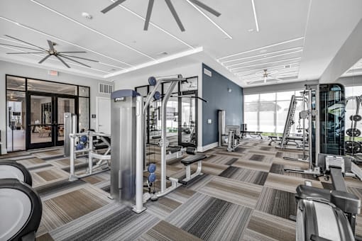 A spacious gym with a variety of equipment and a ceiling fan.
