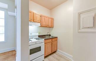 kitchen with wood cabinetry, gas range and view of living area at twin oaks apartments columbia heights washington dc