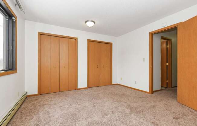 an empty living room with three doors and carpeting. Anoka, MN Dellwood Estates