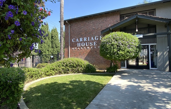 a sidewalk in front of a building with a sign that reads carriage house