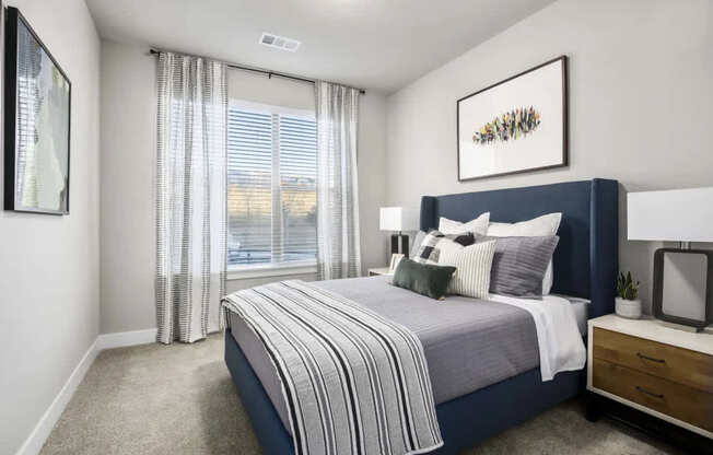 A bedroom with a large bed and a window with curtains.