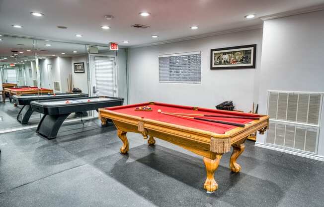 two pool tables in a game room with other billiard tables