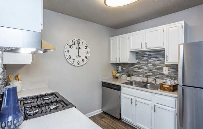 an open kitchen with a large clock on the wall and a stove and sink