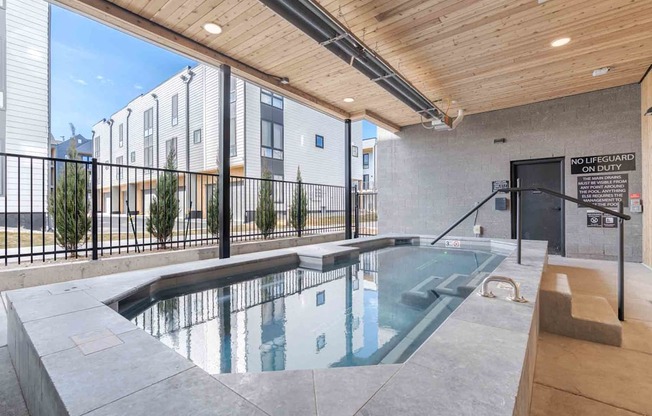 A pool with a black fence and a sign that says no lifeguard on duty.