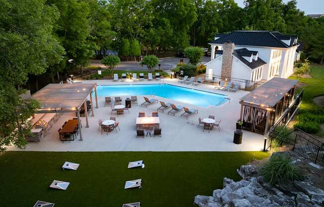 a backyard with a pool and a patio with tables and chairs