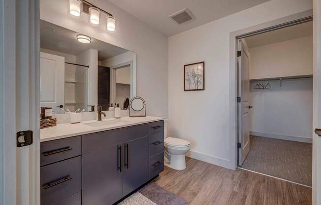 A bathroom with a toilet, sink, and mirror.