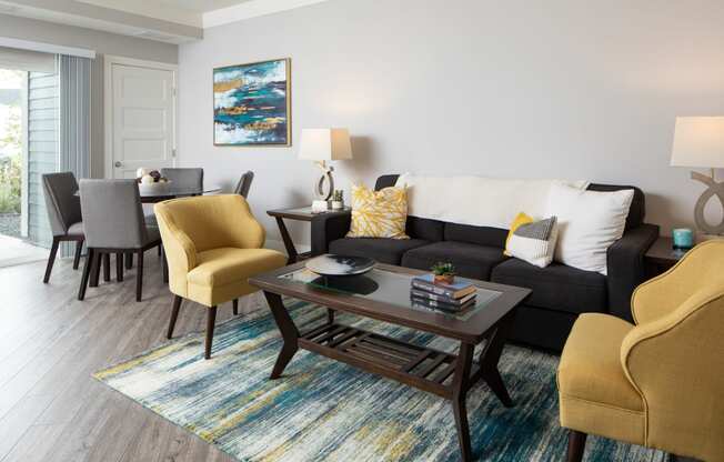 a living room with a couch coffee table and chairs and a dining room table in the background