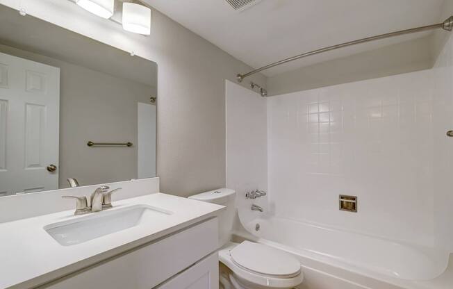 Apartments in Aurora, CO 80011 for Rent – Aurora Meadows - A white bathroom with a sink, toilet, and bathtub.