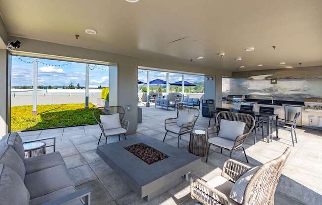 A patio with a fire pit and chairs.