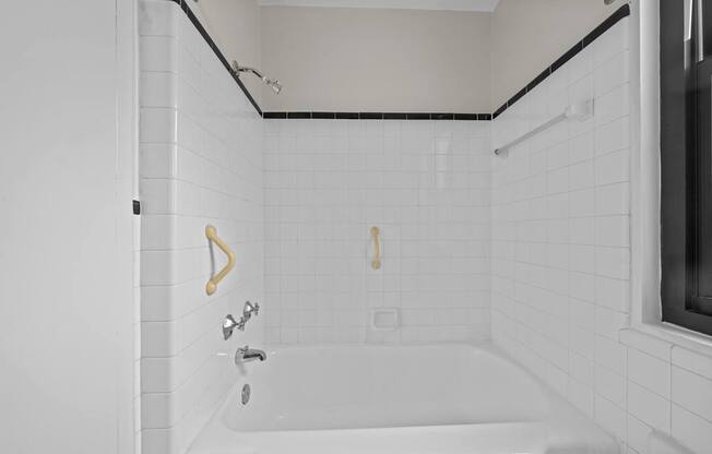 A white bathroom with a white tub and white tiles.