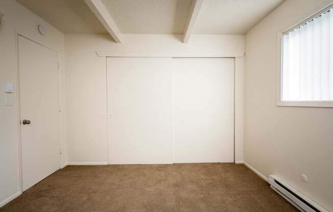 A room with a brown carpet and white walls.