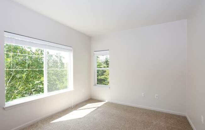A room with white walls and carpeted floor with two windows at Wilsonville Summit Apartments, Wilsonville  97070