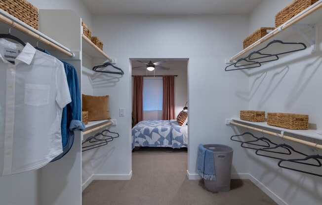 a walk in closet with shelves and racks and a bedroom with a bed