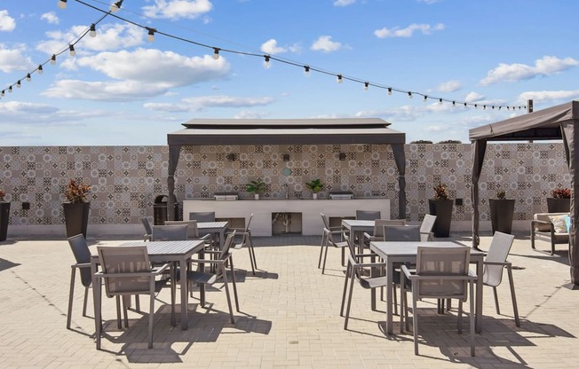 A patio with tables and chairs and a wall with tiles.