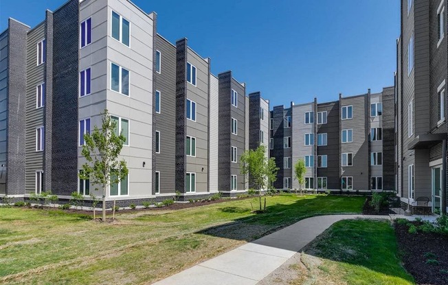 an exterior view of an apartment building with grass and trees