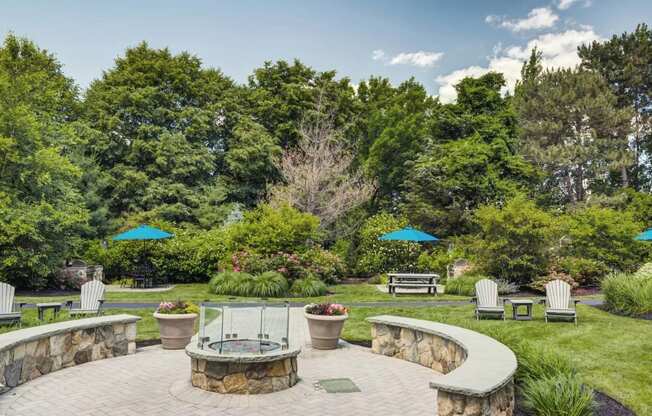 a patio with a fire pit and benches in a garden