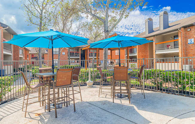 A patio with chairs and umbrellas in front of a brick building.
