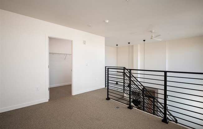 a room with white walls and a railing and a closet