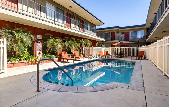 A small pool surrounded by a fence and chairs.