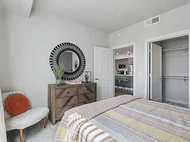A bedroom with a bed, chair, and a mirror on the wall.