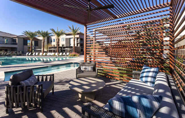 A patio with a pool and a wooden pergola.