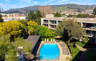 an aerial view of a swimming pool with a hotel in the background