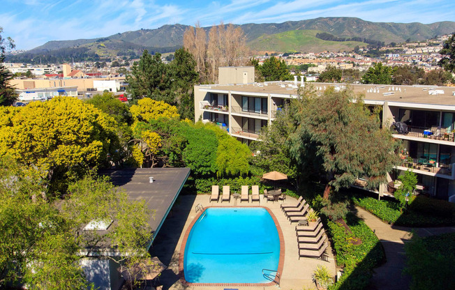 an aerial view of a swimming pool with a hotel in the background