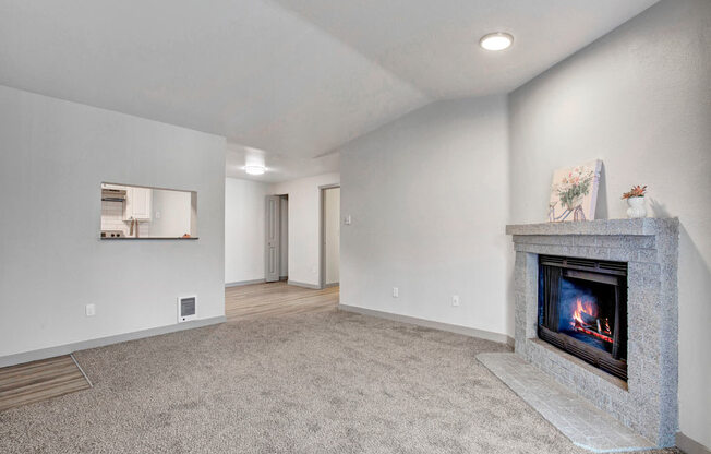 a living room with a fireplace and a kitchen in the background